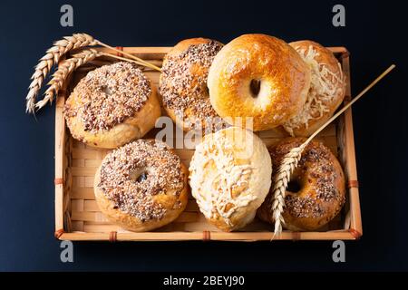 Food bakery concept Homemade organic bagels in bamboo wicker tray on black background Stock Photo