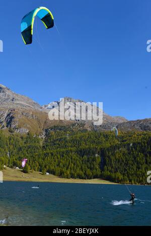 Mountain landscape with a lot of kite surfers and windsurfers moving in a lake. They use the wind to move their boards on the water Stock Photo