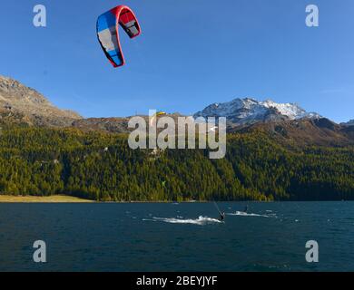 Mountain landscape with a lot of kite surfers and windsurfers moving in a lake. They use the wind to move their boards on the water Stock Photo