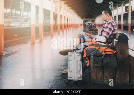 Traveler sitting and using map at train station. Stock Photo