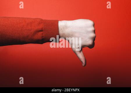 Man hand shows thumb down on red background. Stock Photo