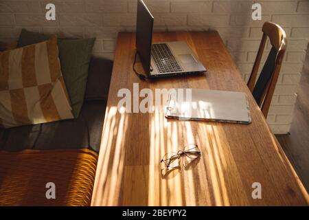 Minimalistic workplace at home on a wooden table in the shadows. Stock Photo
