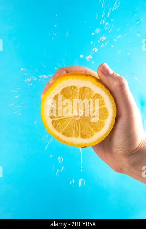 Yellow lemon in hand with drops of juice Stock Photo