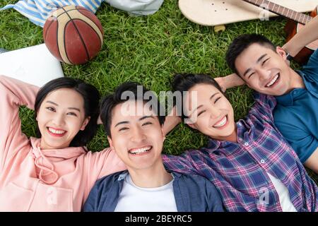 Happy students lay on the grass Stock Photo