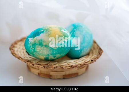 Spring Easter chicken multicolored eggs of blue color in a wicker basket on a white background. horizontal Stock Photo
