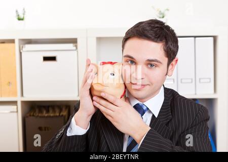 Young businessman with piggy bank in hand in the office Stock Photo
