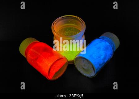 Photoluminescence chemical materials, called fluorescent. Powder glows in the dark under UV light radiation of different colors. For OLED displays man Stock Photo