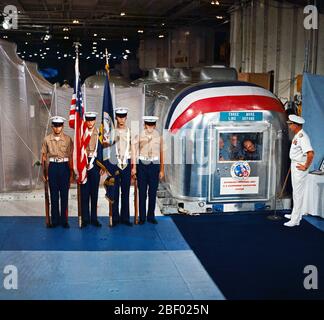 Rear Admiral Donald C. David, Commander, Manned Spacecraft Recovery Force, Pacific, welcomes the crew of the Apollo 12 lunar landing mission aboard the USS Hornet, prime recovery vessel for the mission. A color guard was also on hand for the welcoming ceremonies. Inside the Mobile Quarantine Facility (MQF) are (left to right) astronauts Charles Conrad Jr., commander; Richard F. Gordon Jr., command module pilot; and Alan L. Bean, lunar module pilot. Stock Photo