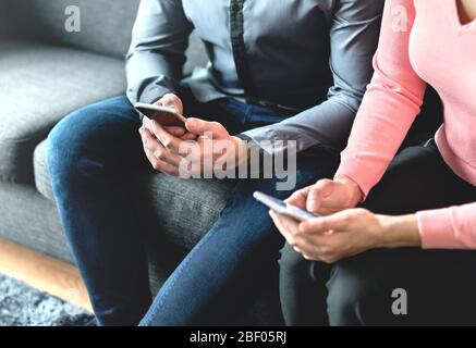 Two people using mobile phones. Business partners, friends or couple looking at their smartphones. Man and woman exchanging numbers during meeting. Stock Photo