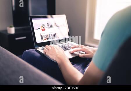 Social media profile on screen. Man using laptop at home. Personal online page. Business network website mockup. Writing status update. Stock Photo
