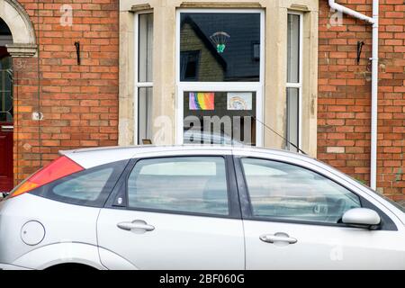 Chippenham, Wiltshire UK, 16th April, 2020. With the nation due to once again clap to show their support for the NHS tonight, a childs drawing of a rainbow (a symbol of support for people wanting to show solidarity with NHS workers) is pictured in a front window of a home in Chippenham, Wiltshire. Credit: Lynchpics/Alamy Live News Stock Photo