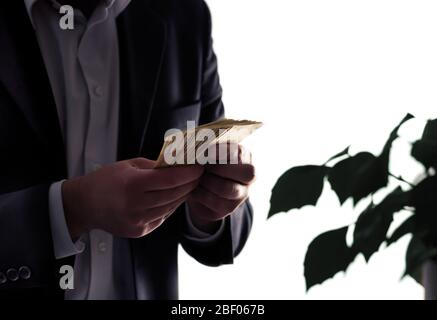 Environment or eco business and finance. Invest to sustainable and green energy. Man in a suit counting money. Plant with leafs. Environmental lawyer. Stock Photo
