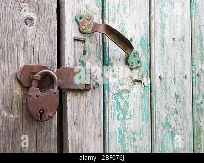 Aging door from boards with padlocks from ferric. Rustic door in shed close-up Stock Photo