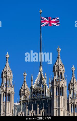 A Union Jack flag flying from, The Victoria Tower, Palace of Westminster commonly known as the Houses of Parliament, which is the meeting place of the Stock Photo