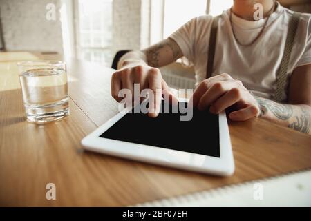 Close up of male hands using tablet with blank screen, copyspace. Surfing, online shopping, scrolling, betting, working. Education, freelance, art and business concept. Watching cinema, reading book. Stock Photo