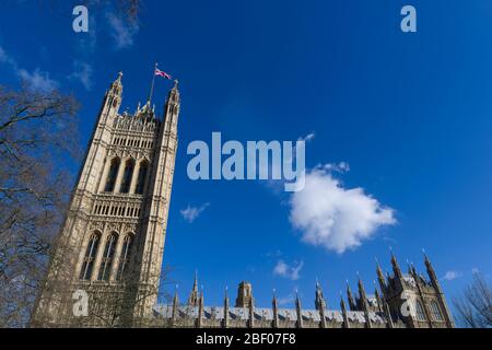 A Union Jack flag flying from, The Victoria Tower, Palace of Westminster commonly known as the Houses of Parliament, which is the meeting place of the Stock Photo