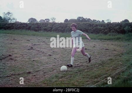 1960s, historical, lady footballer in a light blue, short sleeve shirt and white shorts, playing or practising with a ball in a field, recently mowed, England, UK. Stock Photo
