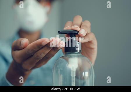 Selective focus on the hands of a black woman using sanitizer gel or soap and wearing a FFP3 mask. Disinfection. Coronavirus. Blurry background. Stock Photo