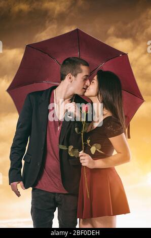 Girlfriend and boyfriend having a passionate kiss framed in one umbrella Stock Photo