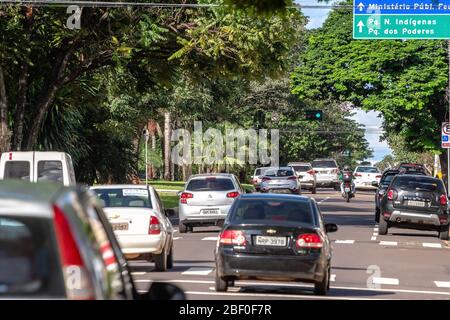 Campo Grande - MS, Brazil - March 30, 2020: Big trees and traffic of cars at Afonso Pena avenue, main avenue of the city. Wooded avenue surrounded by Stock Photo