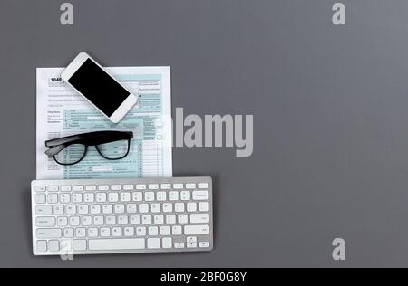 Modern work items to prepare to do personal income taxes on a gray table top with copy space Stock Photo