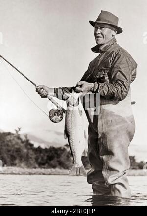 An old fisherman with a white hat is fishing with his fishing pole