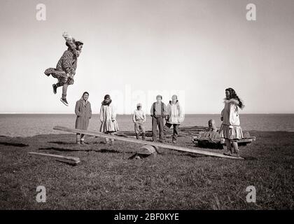 1940s 1950s ALASKAN ESKIMO CHILDREN AND TEENS PLAYING A GAME OF JUMPBOARD A KIND OF SEESAW GAME ARCTIC KOTZEBUE ALASKA USA - c2677 BAU001 HARS LEAPING JOY LIFESTYLE FEMALES ESKIMO RURAL HOME LIFE UNITED STATES COPY SPACE FULL-LENGTH PHYSICAL FITNESS PERSONS SEESAW INDIANS UNITED STATES OF AMERICA MALES TEENAGE GIRL TEENAGE BOY B&W NORTH AMERICA NORTH AMERICAN ALASKA HUMOROUS LEAP AND RECREATION COMICAL INUIT COMEDY KIND TEENAGED KOTZEBUE NATIVE AMERICAN ARCTIC COOPERATION GROWTH JUVENILES NATIVE AMERICANS PRE-TEEN PRE-TEEN BOY PRE-TEEN GIRL TOGETHERNESS ALASKAN BLACK AND WHITE INDIGENOUS Stock Photo