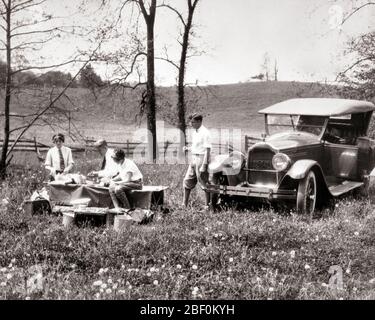1920s GROUP OF FRIENDS TWO COUPLES MEN WOMEN ENJOYING PICNIC IN RURAL COUNTRY FIELD CONVERTIBLE TOURING CAR PARKED NEARBY - c1751 HAR001 HARS HEALTHINESS PREPARING COPY SPACE FRIENDSHIP FULL-LENGTH LADIES PERSONS AUTOMOBILE MALES PLANNING TRANSPORTATION B&W PARKED FREEDOM HAPPINESS LEISURE AUTOS ENJOYING RECREATION IN OF THEM CONCEPTUAL AUTOMOBILES ESCAPE STYLISH VEHICLES NEARBY COOPERATION MID-ADULT RELAXATION TOGETHERNESS YOUNG ADULT MAN YOUNG ADULT WOMAN BLACK AND WHITE CAUCASIAN ETHNICITY HAR001 OLD FASHIONED TOURING Stock Photo