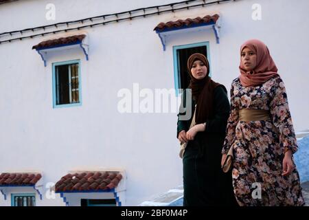 Chefchaouen, northern Morocco, 10th June 2016. Two Moroccan girls walk and talk on one of the city streets. Stock Photo