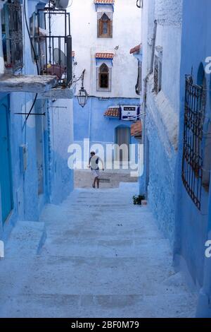 Chefchaouen, northern Morocco, 10th June 2016. A young man runs up the steps of a street in the old city, the blue city. Stock Photo
