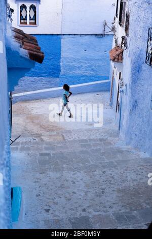 Chefchaouen, northern Morocco, 10th June 2016. A child plays in front of the door of his house in the blue city. Stock Photo