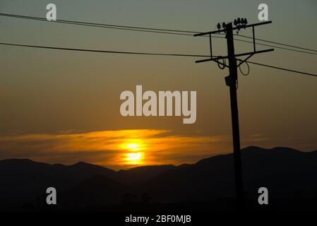 sunset behind electricity pole over mountain range in little karoo, south africa Stock Photo