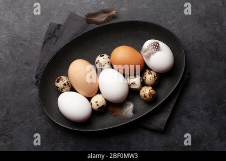 White, brown and quail eggs on stone table. Top view. Flat lay Stock Photo