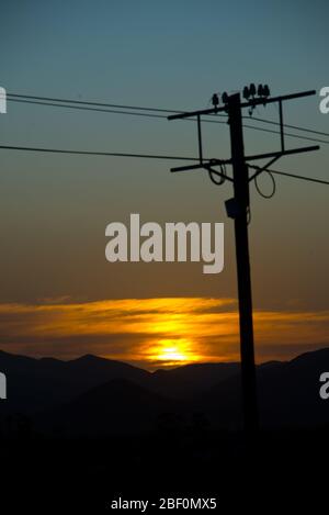 sunset behind electricity pole over mountain range in little karoo, south africa Stock Photo