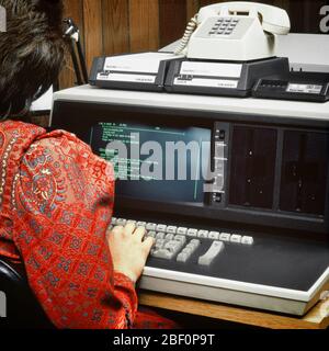 1980s BACK OF ANONYMOUS WOMAN WEARING RED PAISLEY DRESS WORKING ON EARLY COMPUTER TERMINAL KEYBOARD WITH DIAL-UP TELEPHONE MODEM - ko1556 PHT001 HARS FEMALES JOBS UNITED STATES COPY SPACE LADIES PERSONS UNITED STATES OF AMERICA NORTH AMERICA NORTH AMERICAN SKILL OCCUPATION SKILLS HEAD AND SHOULDERS EARLY PAISLEY REAR VIEW OF ON OPPORTUNITY EMPLOYMENT OCCUPATIONS HIGH TECH DATA ENTRY HARDWARE MONITOR ANONYMOUS EMPLOYEE BACK VIEW DIAL-UP HIGH-TECH MODEM PROGRAMMER TERMINAL YOUNG ADULT WOMAN CAUCASIAN ETHNICITY OLD FASHIONED Stock Photo