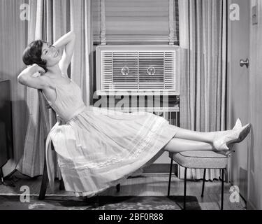 1950s 1960s SMILING BRUNETTE WOMAN ARMS OVER HEAD RESTING RELAXING IN FRONT OF WINDOW AIR CONDITIONING UNIT  - s11464 DEB001 HARS LADIES PERSONS B&W RESTING BRUNETTE COMFORT HAPPINESS CHEERFUL COMFORTABLE PROGRESS UNIT CONDITIONING INNOVATION SMILES AIR CONDITIONER JOYFUL STYLISH DEB001 COOLING HVAC SOLUTIONS SPAGHETTI STRAP YOUNG ADULT WOMAN BLACK AND WHITE CAUCASIAN ETHNICITY OLD FASHIONED Stock Photo