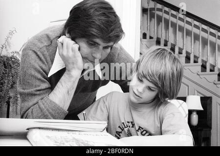 1970s FATHER HELPING HIS SON WITH HOMEWORK LEANING ELBOW ON TABLE LOOKING OVER THE BOY’S SHOULDER   - s19638 HAR001 HARS ELEMENTARY COMMUNICATION TEAMWORK STRONG SONS FAMILIES JOY LIFESTYLE PARENTING COPY SPACE PERSONS INSPIRATION CARING MALES TEENAGE BOY FATHERS B&W SCHOOLS SUCCESS GRADE HAPPINESS HEAD AND SHOULDERS ADVENTURE DISCOVERY HIS DADS EXCITEMENT KNOWLEDGE POWERFUL AUTHORITY ELBOW PRIMARY CONNECTION CONCEPTUAL CAREGIVER SUPPORT KID'S PERSONAL ATTACHMENT AFFECTION EMOTION GRADE SCHOOL GROWTH JUVENILES MID-ADULT MID-ADULT MAN TOGETHERNESS BLACK AND WHITE CAUCASIAN ETHNICITY HAR001 Stock Photo