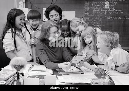 1970s 1980s DIVERSE GROUP OF SCHOOL CHILDREN BOYS AND GIRLS AROUND TEACHER HOLDING OPEN BOOK AT HER DESK - s21516 HAR001 HARS HER ASIAN OLD TIME FUTURE NOSTALGIA READ CHALKBOARD OLD FASHION JUVENILE DIVERSE TEACHERS COMMUNICATION LAUGH SPANISH INFORMATION PLEASED JOY LIFESTYLE FEMALES COPY SPACE FRIENDSHIP HALF-LENGTH LADIES PERSONS INSPIRATION MALES CONFIDENCE B&W HAPPINESS CHEERFUL HIGH ANGLE ORIENTAL AFRICAN-AMERICANS AFRICAN-AMERICAN AND EXCITEMENT INSTRUCTOR KNOWLEDGE BLACK ETHNICITY ASIAN AMERICAN OCCUPATIONS SMILES CONCEPTUAL EDUCATOR JOYFUL ASIAN-AMERICAN COOPERATION EDUCATING Stock Photo