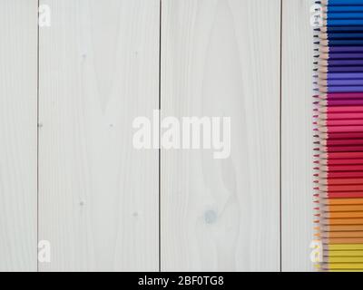 Set of colored pencils arranged in a row on wooden background. top view Stock Photo