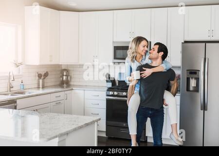 young married couple flirting in their clean kitchen Stock Photo
