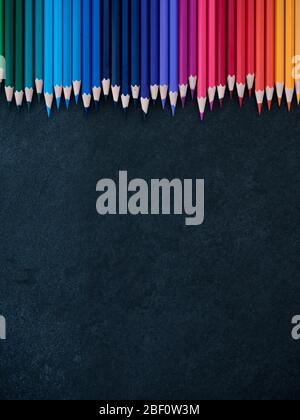 Set of colored pencils arranged in a row on slate background. top view Stock Photo