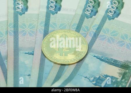 Russian money paper bills of one thousand rubles denominated in a fan. Bitcoin is on top. Stock Photo