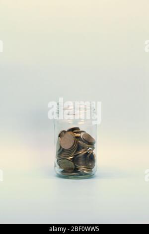 Metal coins, Russian rubles, lie in a transparent glass jar on a light background. Place for text and design. Stock Photo