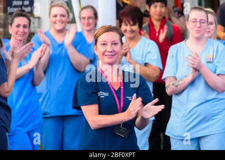 Dorchester, Dorset, UK.  16th April 2020.  Frontline staff including doctors, nurses, police and fire and rescue staff clap for carers, key workers and NHS staff outside the entrance to the A&E department at Dorset County Hospital at Dorchester in Dorset during the coronavirus pandemic lockdown.  Picture Credit: Graham Hunt/Alamy Live News Stock Photo