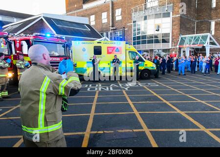 Dorchester, Dorset, UK.  16th April 2020.  Frontline staff including doctors, nurses, police and fire and rescue staff clap for carers, key workers and NHS staff outside the entrance to the A&E department at Dorset County Hospital at Dorchester in Dorset during the coronavirus pandemic lockdown.  Picture Credit: Graham Hunt/Alamy Live News Stock Photo