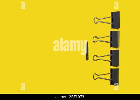 four big paper clips against small pencil Stock Photo