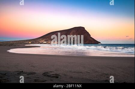 Colorful sky after sunset at La Tejita beach with the iconic 'Red Hill' (La Montaña Roja) in the South of Tenerife, Canary Islands, Spain. Stock Photo