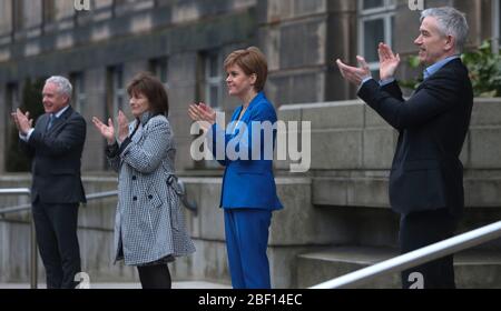 (left to right) Malcolm Wright Director General Chief Executive NHS Scotland, Health Secretary Jeane Freeman, First Minister Nicola Sturgeon and Dr Gregor Smith Scotland's interim chief medical officer applaud outside St Andrew's House, the headquarters building of the Scottish Government in Edinburgh, to salute local heroes during Thursday's nationwide Clap for Carers initiative to recognise and support NHS workers and carers fighting the coronavirus pandemic. Stock Photo