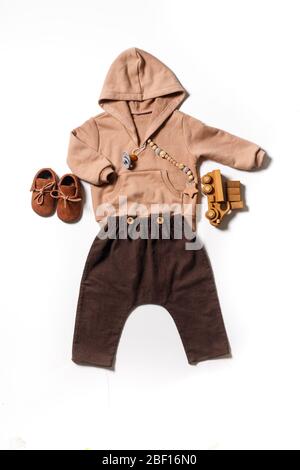 flatlay of children's clothing, children's brown shoes shoes for autumn, brown trousers and beige hoodie, top View. Stock Photo