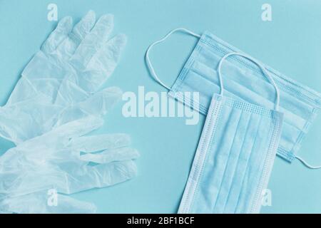 Blue medical face mask and disposable white gloves on blue background. Stock Photo